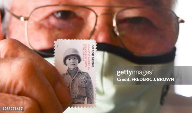 World War 2 US military veteran who served in the 442nd Regimental Combat Team, Yosh Nakamura displays the latest US postage stamp, "Go For Broke:...