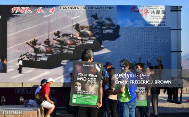 Activists carry petitions to end the CCP in front of the iconic "Tank Man" photograph on display at Liberty Sculpture Park in the Mojave desert town...