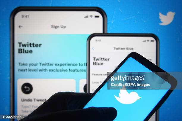 In this photo illustration, Twitter logo is seen on a smartphone in a hand in front of a Twitter webpage about launch new subscription service...
