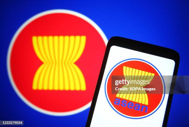 In this photo illustration, ASEAN emblem is seen on a smartphone screen in front of the ASEAN flag.