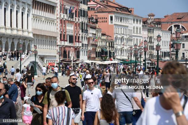 Tourists stroll along tje basin near the Ponte della Paglia bridge in Venice on June 05, 2021.