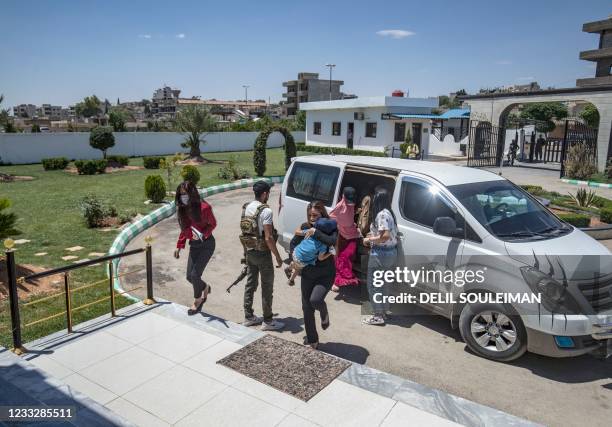 Members of Kurdish security forces accompany relatives of Islamic State group fighters, before handing them over to a delegation of Dutch diplomats...