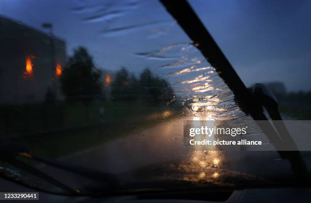 June 2021, Bavaria, Iphofen: Behind a windshield wiper, a car drives along a road in heavy rain. Photo: Karl-Josef Hildenbrand/dpa