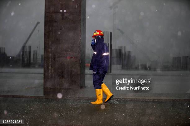 Worker walks in rain at a construction site of Hazrat Shahjalal International Airports third terminal in Dhaka, Bangladesh on June 05, 2021. The...