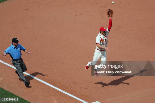 Nolan Arenado of the St. Louis Cardinals attempts to catch a throw to him against the Cincinnati Reds as umpire Dan Iassogna looks on in the seventh...