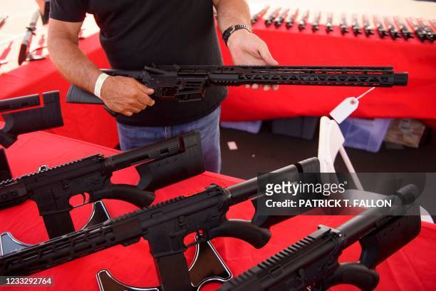 Clerk shows a customer a California legal, featureless AR-15 style rifle from TPM Arms LLC on display for sale at the company's booth at the...