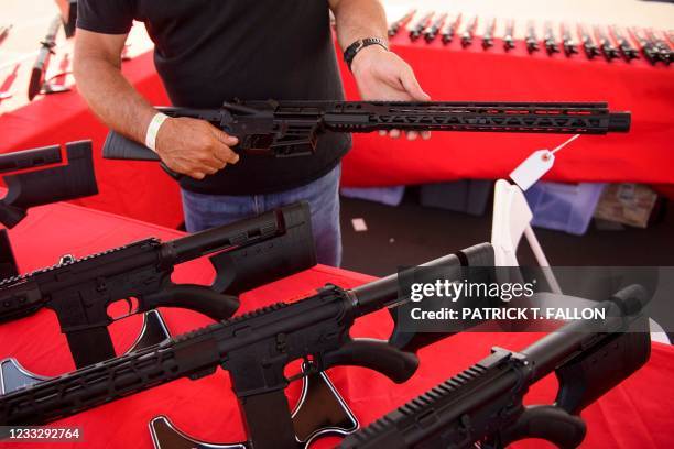 Clerk shows a customer a California legal, featureless AR-15 style rifle from TPM Arms LLC on display for sale at the company's booth at the...