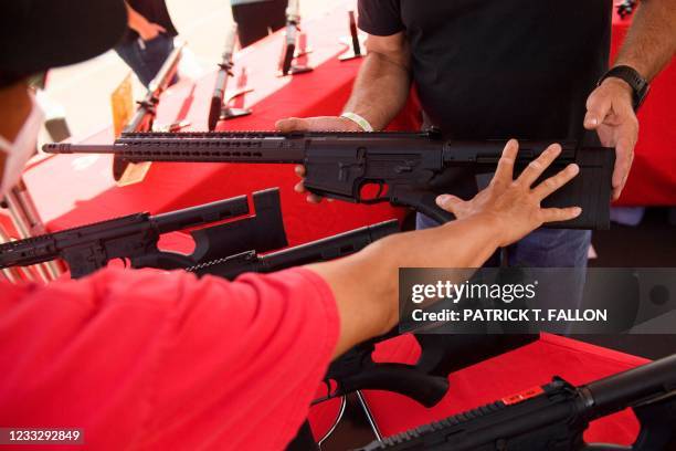 Clerk shows a customer a TPM Arms LLC California-legal featureless AR-10 style .308 rifle displayed for sale at the company's booth at the Crossroads...