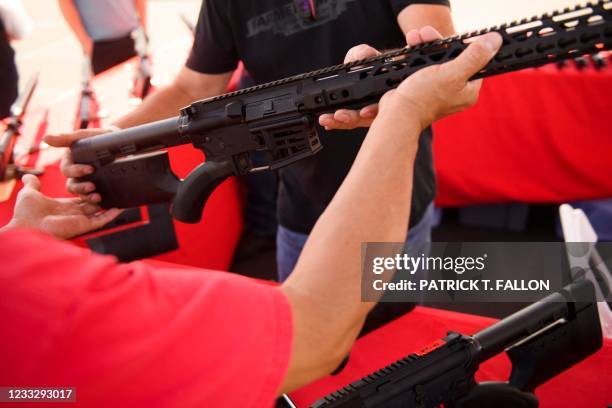 Clerk hands a customer a California legal, featureless AR-15 style rifle from TPM Arms LLC on display for sale at the company's booth at the...