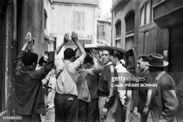 Algerian suspects with hands up are arrested shortly after a car bomb exploded in a street of Constantine on August 24 during the Algerian war, after...