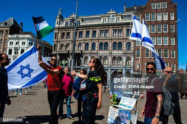 Palestinian demonstrator holding a flag and shows a middle finger to an Israel flag during a pro Palestine demonstration at the Dam Square in...