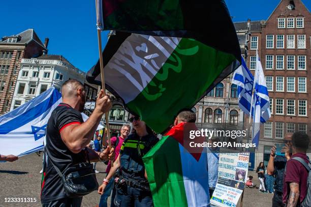 Two Palestinian demonstrators holding flags speak with a police officer during a pro Palestine demonstration at the Dam Square in Amsterdam. During a...