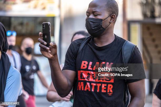 Protester dressed in the Black Lives Matter shirt doing recordings on his mobile phone, during the demonstration. Summoned by Black Community...