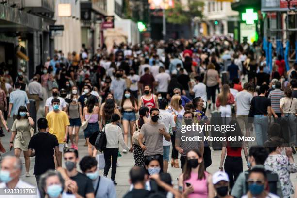 Crowds wearing face masks to stop the spread of coronavirus walk in Preciados Street, a shopping area near Sol Square in downtown Madrid.