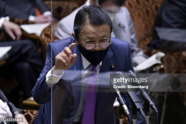 Taro Aso, Japan's deputy prime minister and finance minister, wears a protective face mask while speaking from behind a transparent screen during an...