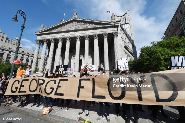 Protesters gather behind a banner spelling the name of George Floyd, a black man who died after a white policeman kneeled on his neck for several...