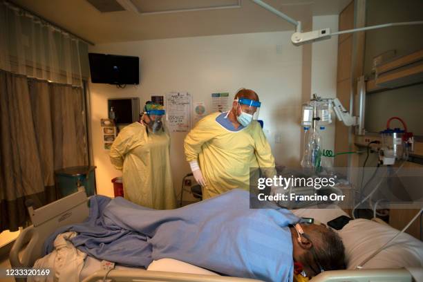 Registered Nurse Jess Esperti, left, and Dr. Ameer Moussa right, work with covid patient Mariano Zuniga-Anaya, 57 in ICU at Martin Luther King, Jr....