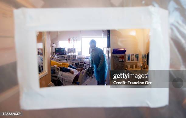 View of pulmonologist Dr. Jason Prasso through a plastic door after he was checking on patient Gilbert Torres, age 30, inside Martin Luther King, Jr....