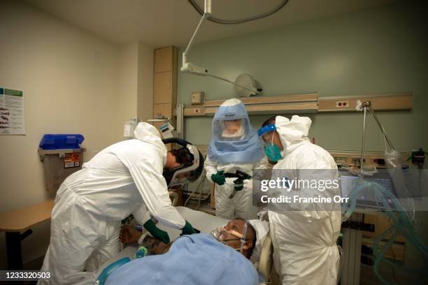 Nurse Christopher Fernandez, left, Dr. Stefan Richter, middle, and a respretory therapist, right, works on Mariano Zuniga-Anaya middle, in the ICU at...