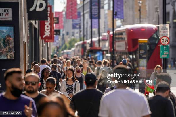 Pedestrians, some wearing face coverings due to Covid-19, walk past shops on Oxford Street in central London on June 7, 2021. - The Delta variant of...