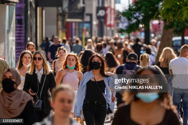Pedestrians, some wearing face coverings due to Covid-19, walk past shops on Oxford Street in central London on June 7, 2021. - The Delta variant of...
