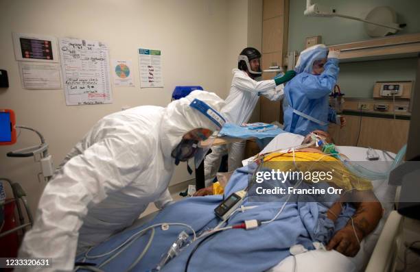 Registered Nurse Jess Esperti, left, ICU nurse Christopher Fernandez, middle, and Dr. Stefan Richter, right, in blue hood work on Mariano...