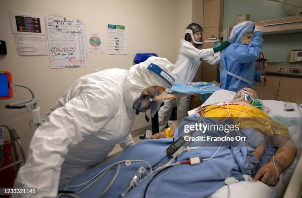 Registered Nurse Jess Esperti, left, ICU nurse Christopher Fernandez, middle, and Dr. Stefan Richter, right, in blue hood work on Mariano Zuñiga...