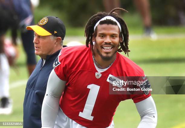 Foxborough, MA Quarterback Cam Newton warms up as coach Bill Belichick walks by. The New England Patriots held OTAs at their practice field at...