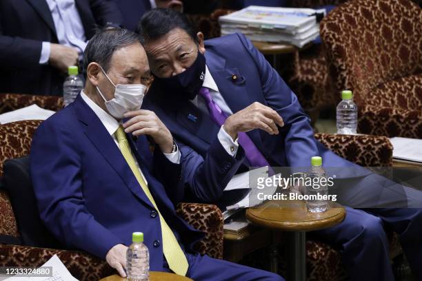 Yoshihide Suga, Japan's prime minister, left, and Taro Aso, deputy prime minister and finance minister, wear protective face masks while talking...