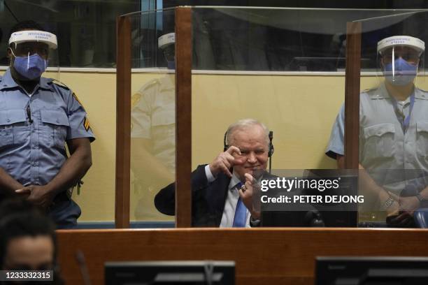 Ex-Bosnian Serb military chief Ratko Mladic imitates taking pictures as he sits in the defendant box prior to the hearing of the final verdict on...