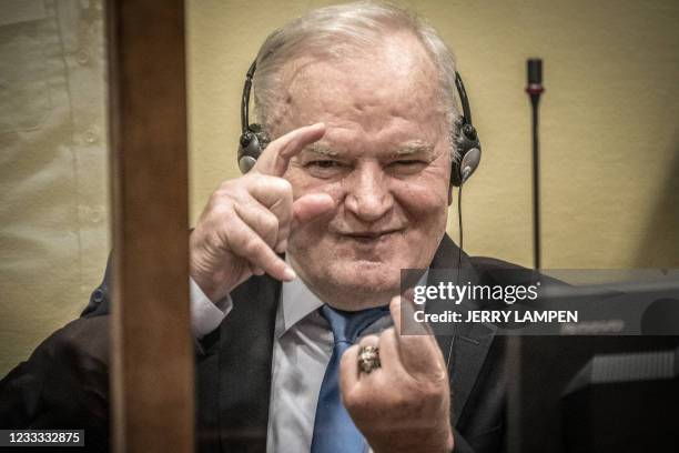 Ex-Bosnian Serb military chief Ratko Mladic imitates taking pictures as he sits in the defendant box prior to the hearing of the final verdict on...