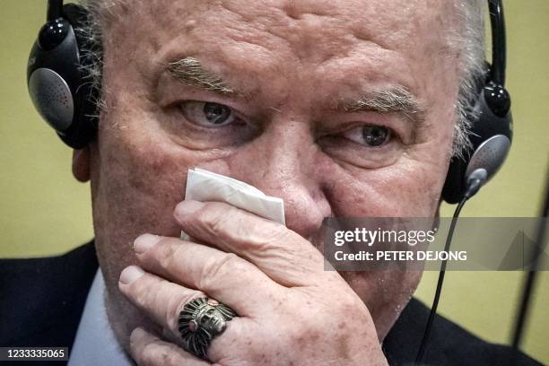 Ex-Bosnian Serb military chief Ratko Mladic wipes his face as he sits in the defendant box during the earing of the final verdict on appeal against...