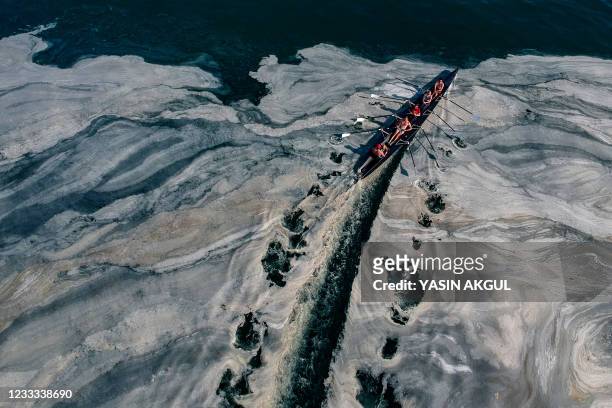 This aerial photograph taken on June 8, 2021 on the Caddebostan shore of Turkey's Marmara Sea, shows a boat sailing among mucilage, a jelly-like...