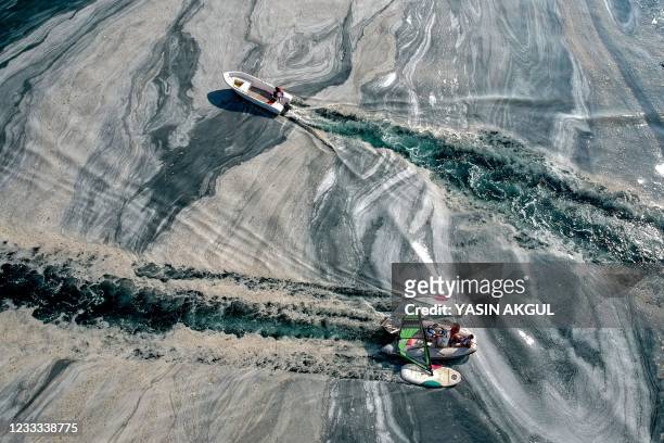This aerial photograph taken on June 8, 2021 on the Caddebostan shore of Turkey's Marmara Sea, shows a boat sailing among mucilage, a jelly-like...