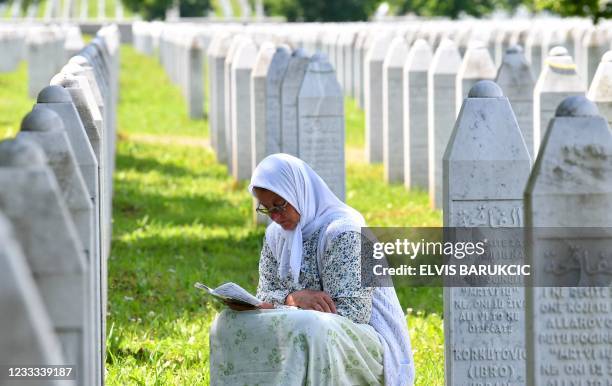 Bosnian Muslim woman reads from a book of prayers among grave stones of her relatives who fell as victims of Srebrenica 1995 massacre, on June 8 at...