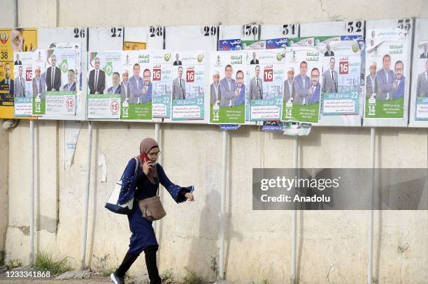 Woman walks past the banners of candidates hung on the walls of streets and vehicles ahead of the early general elections scheduled for June 12, in...