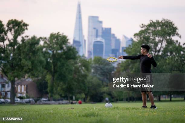 With the Shard and the capital's financial district in the distance, a young man throws a frisbee through the air towards an unseen opponent in...
