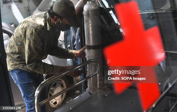 Mechanic fixes an oxygen cylinder in a car that is being converted into an ambulance with an oxygen cylinder in Bengaluru. An initiative by "Drive...