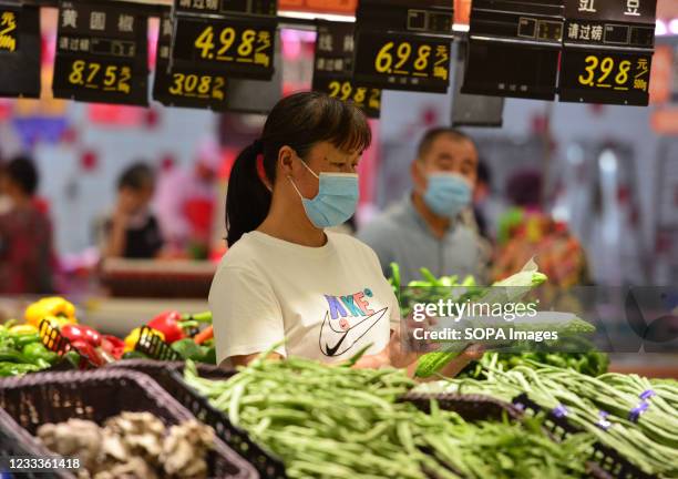 Woman shops for fresh vegetables at RT Mart supermarket. China's consumer price index, a main gauge of inflation, grew by 1.3 percent year-on-year...