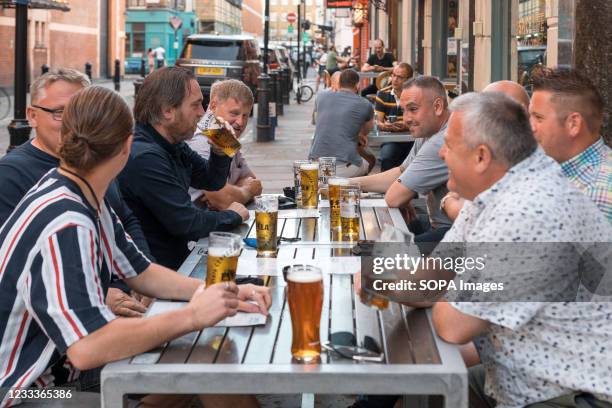 People seen drinking beer at a bar in Soho, London As the UK government lifted the restrictions imposed on dining services in relation to COVID,...