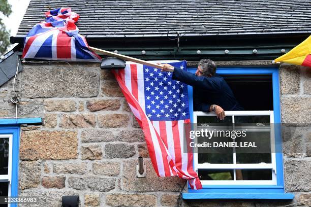 The owner of The Cornish Arms gastropub adjusts the Union Flag alongside the American Flag displayed on the exterior of the pub in St Ives, Cornwall...