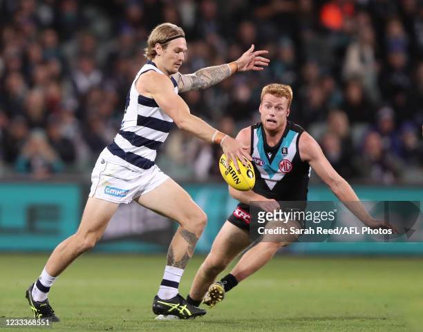 Tom Stewart of the Cats kicks the ball against Willem Drew of the Power during the 2021 AFL Round 13 match between the Port Adelaide Power and the...
