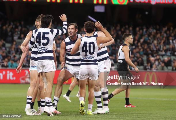 Tom Hawkins of the Cats celebrates a goal with team mates as Karl Amon of the Power walks away during the 2021 AFL Round 13 match between the Port...