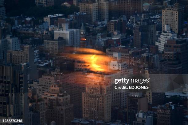 Partial solar eclipse is reflected on a glass panel before buildings of the Manhattan skyline, from the Edge viewing deck in New York on June 10,...