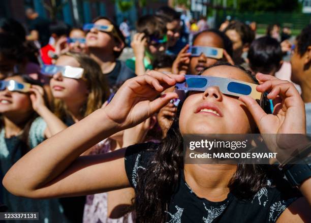 Pupils, wearing protective glasses, look at the partial solar eclipse in Schiedam on June 10, 2021. - A solar eclipse will be visible over the...