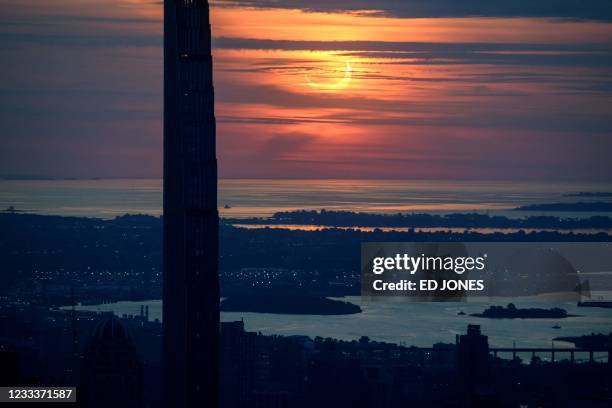 Partial solar eclipse rises between buildings of the Manhattan skyline from the Edge viewing deck in New York on June 10, 2021. - Northeast states in...