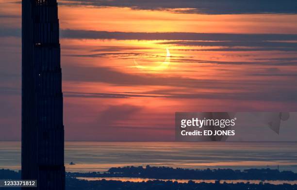 Partial solar eclipse rises between buildings of the Manhattan skyline from the Edge viewing deck in New York on June 10, 2021. - Northeast states in...