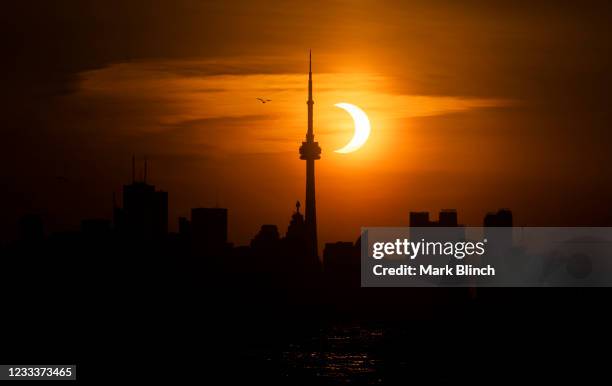 The sun rises behind the skyline during an annular eclipse on June 10, 2021 in Toronto, Canada. Across parts of Canada, viewers witnessed the rare...