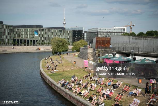 Guests enjoy the sunny weather outside at a beach bar on the bank of the Spree river in Berlin on June 10, 2021 amid the ongoing coronavirus COVID-19...