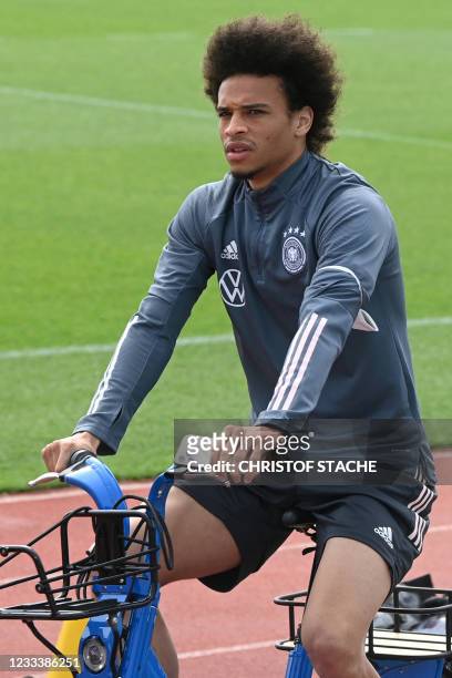 Germany's midfielder Leroy Sane arrives on a bicycle before a training session at the World of Sports Campus in Herzogenaurach on June 11, 2021 ahead...
